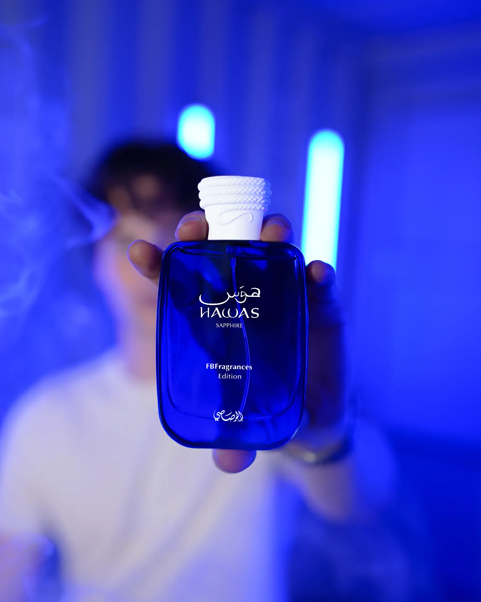 Hawas Sapphire bottle held against electric blue light
